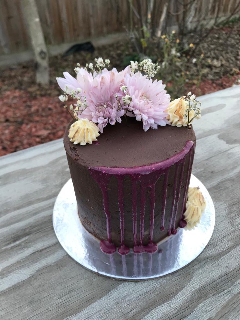 chocolate cake with purple drip and flower arrangement on top